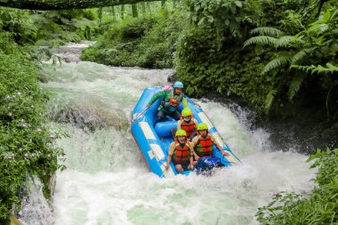 Pangalengan, Bandung-Endonezya Aralık 2022: Bir grup erkek ve kadın nehir üzerinde rafting yapıyorlar, ekstrem ve eğlenceli spor. Bir grup insan su sporları rafting