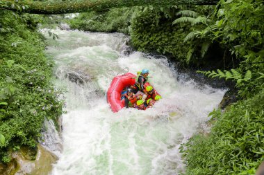 Pangalengan, Bandung-Endonezya Aralık 2022: Bir grup erkek ve kadın nehir üzerinde rafting yapıyorlar, ekstrem ve eğlenceli spor. Bir grup insan su sporları rafting