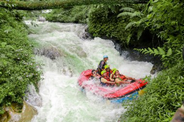 Pangalengan, Bandung-Endonezya Aralık 2022: Bir grup erkek ve kadın nehir üzerinde rafting yapıyorlar, ekstrem ve eğlenceli spor. Bir grup insan su sporları rafting