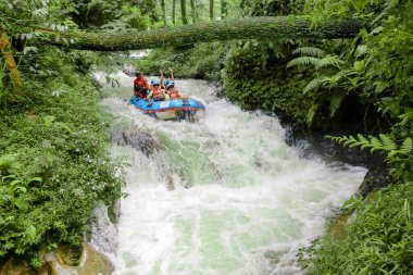 Pangalengan, Bandung-Endonezya Aralık 2022: Bir grup erkek ve kadın nehir üzerinde rafting yapıyorlar, ekstrem ve eğlenceli spor. Bir grup insan su sporları rafting