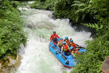 Pangalengan, Bandung-Endonezya Aralık 2022: Bir grup erkek ve kadın nehir üzerinde rafting yapıyorlar, ekstrem ve eğlenceli spor. Bir grup insan su sporları rafting