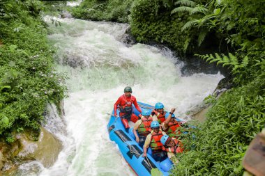 Pangalengan, Bandung-Endonezya Aralık 2022: Bir grup erkek ve kadın nehir üzerinde rafting yapıyorlar, ekstrem ve eğlenceli spor. Bir grup insan su sporları rafting