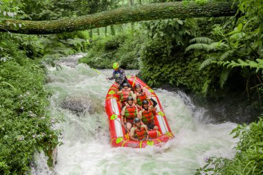 Pangalengan, Bandung-Endonezya Aralık 2022: Bir grup erkek ve kadın nehir üzerinde rafting yapıyorlar, ekstrem ve eğlenceli spor. Bir grup insan su sporları rafting