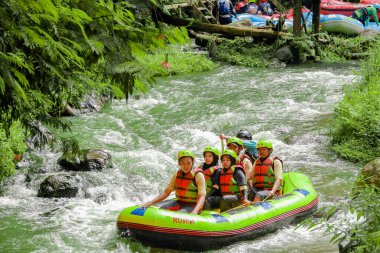 Pangalengan, Bandung-Endonezya Aralık 2022: Bir grup erkek ve kadın nehir üzerinde rafting yapıyorlar, ekstrem ve eğlenceli spor. Bir grup insan su sporları rafting