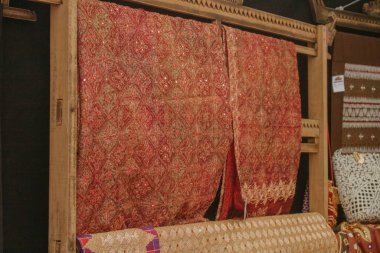 Kumaş çeşitliliği. Raflarda farklı kumaşlar sergileniyor. Endonezya 'nın Lampung eyaletinden tipik tapis kumaşı olarak adlandırılabilecek bir kumaş..