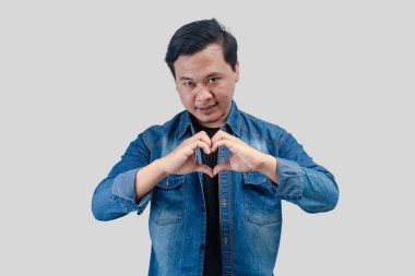 Aşık genç Asyalı adam elleriyle kalp sembolü yapıyor. romantik kavram.