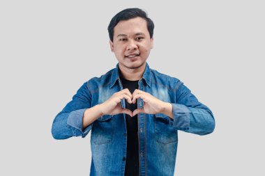 Aşık genç Asyalı adam elleriyle kalp sembolü yapıyor. romantik kavram.