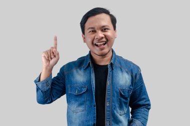 Asyalı genç adam izole edilmiş arka planda elini boş bir alana doğrultuyor.