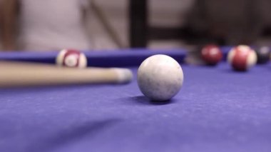 Bilardo sopası beyaz topa vuruyor ve bilardo masasında sayı yapıyor. Mavi bir masa üzerinde kırmızı topla sayı yapmak..