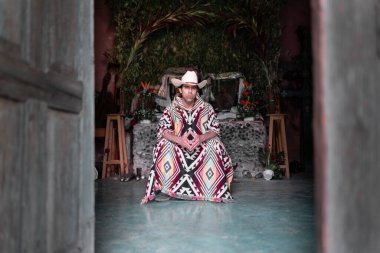 Kilisenin içinde şapkası ve pançosu olan genç bir Meksikalı oturuyor. Geleneksel kıyafet kavramı