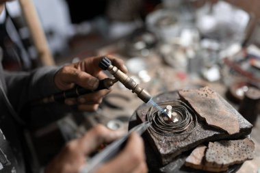 Bir kuyumcu bir mücevher yaratmak için lehim ve kıskaç kullanıyor. El işi kavramı