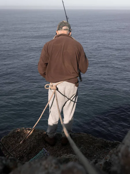 Kıdemli bir balıkçı uçurumun kenarında balık tutarken ipliği tutuyor. Risk işleri kavramı