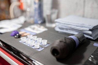 Bazı mürekkep bardakları dövme yapmadan önce diğer aletlerin yanındaki çalışma masasında dinleniyor. Dövme stüdyosunda hijyen kavramı