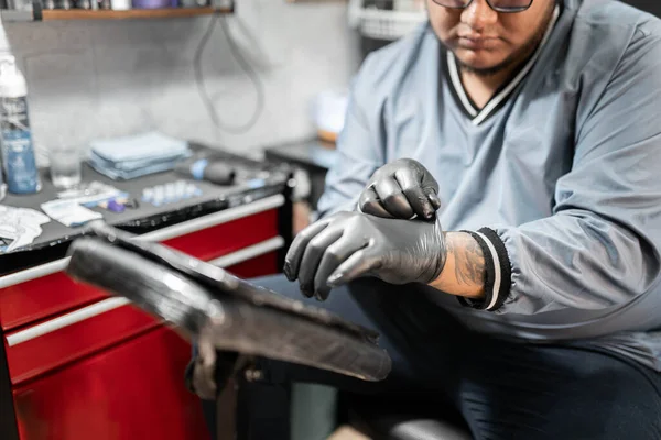 Bir dövme sanatçısı stüdyo istasyonunda dövme yaptırmadan önce lateks eldiven takıyor. Dövme stüdyosunda hijyen kavramı