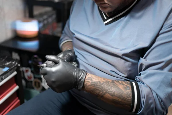 A tattoo artist is setting the needle on the tattoo machine. Concept of hygiene in the tattoo studio