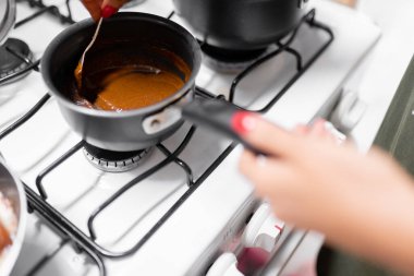 A young woman is preparing mole sauce using a gas stove. Concept of mexican picnic day