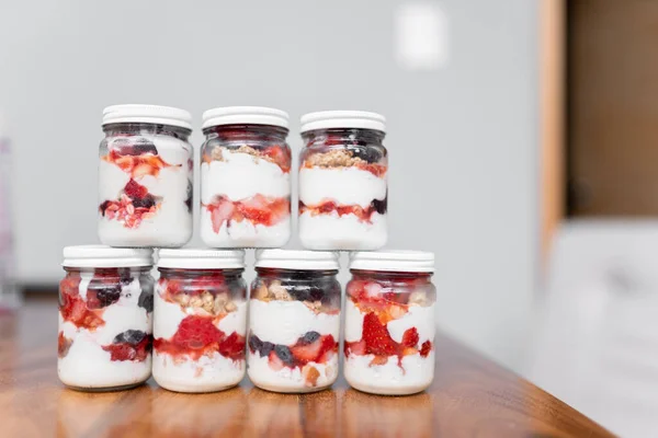 Some jars filled with yogurt, fruits and cereal are on the table before a picnic. Concept of mexican picnic day