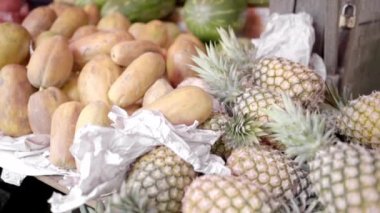 A stack of pineapples, mangos and watermelon are displayed in a Mexican street market stall. Concept of distribution in a traditional mexican market.