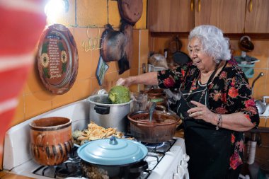 A senior mexican woman is smiling while preparing chayote to go with battered poblano chiles. Concept of mexican traditional cooking
