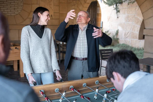 A granddaugther and grandfather are having fun after being scored in table football. Concept of family fun time