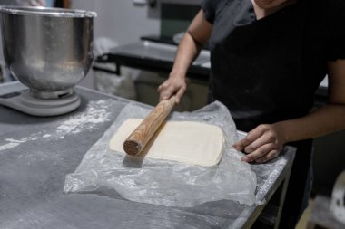 Genç bir İspanyol fırıncı kruvasan hamuru hazırlamak için merdaneyle tereyağını yoğuruyor. Geleneksel Meksika tatlı ekmekleri kavramı