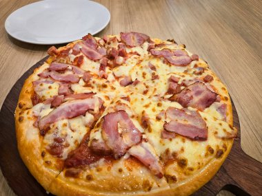 Kalın hamurlu pizza, küp jambon, pastırma ve peynirli tahta tahta.