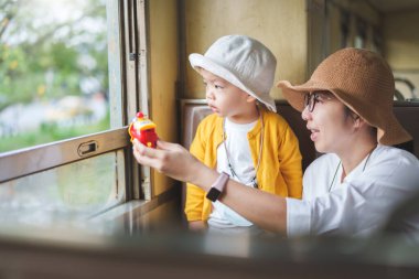 Asian mother and little child boy traveling by train on holiday together