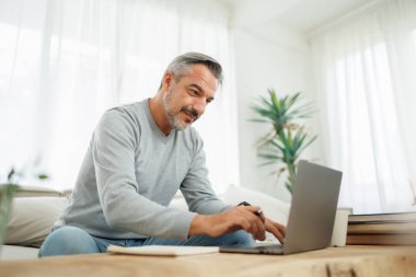 Confident Bearded mature adult man using and typing on laptop, Working at home office, Remote working, freelancer