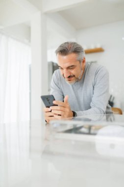 Yetişkin bir adam evde cep telefonu kullanıyor. Son sınıf öğrencisi sabah akıllı telefon kullanıyor. Dikey