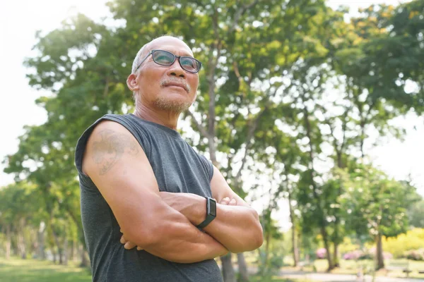 stock image Portrait of Happy and healthy Asian Chinese senior man with arms crossed at park outdoor. Male smiling relaxing, exercising.