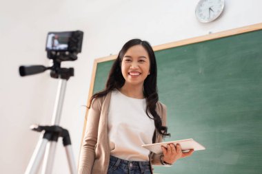 Mutlu Gülümseyen Genç Çekici Asyalı Kadın dijital kameranın önünde konuşuyor.