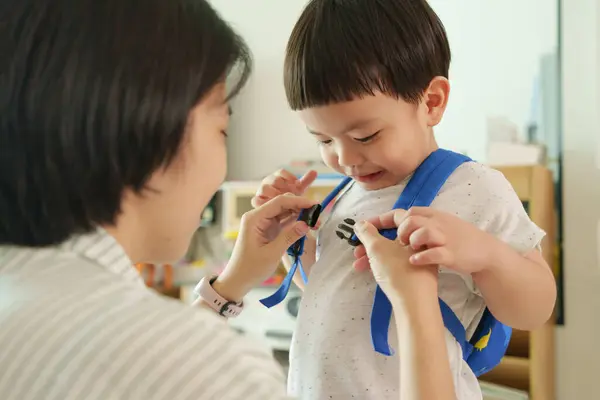 Azjatycka Chińska Matka Pomaga Synowi Zapiąć Pasek Plecaku Przed Wyjazdem Zdjęcia Stockowe bez tantiem