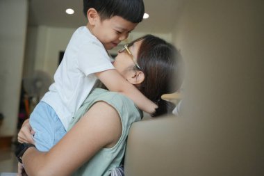 Asyalı anne ve oğlu birbirlerine sarılıyorlar..