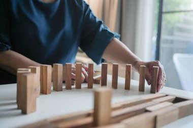 Üst düzey bir kadın beyaz bir masada tahta bloklar düzenliyor, hassasiyet ve denge üzerine odaklanıyor..