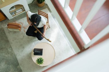 Oturma odasında dijital tablet üzerinde çevrimiçi öğrenme ile birlikte bas gitar pratiği yapan bir adamın genel görünümü.