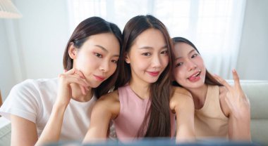 Üç genç Koreli ya da Çinli kadın cep telefonlarıyla neşeli bir selfie çekiyorlar, güzel Asyalı kız gülümsüyor ve neşeli ifadelerle poz veriyor, eğlenceli ve unutulmaz bir arkadaşlık anı yakalıyorlar.