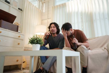 İki Asyalı adam evde futbol maçı izlerken kanepede bira şişeleriyle rahatlıyor. Arkadaşlık kavramı