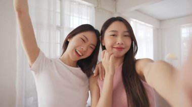 İki Asyalı arkadaş birlikte neşeli bir anı paylaşıyor, kapalı bir alanda neşeli ifadelerle poz veriyorlar..