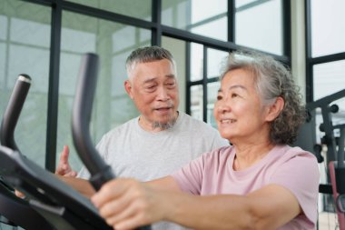 Mutlu Asyalı son sınıf çifti evde birlikte egzersiz yaparken gülümsüyor ve sağlıklı yaşam tarzının tadını çıkarıyor spor salonunda egzersiz yapıyor aktif emeklilik sağlığı motivasyon desteği