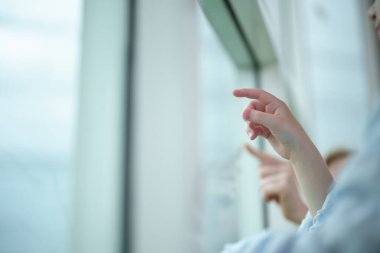 Etrafı yumuşak bir atmosferle çevriliyken iki kız büyük cam pencereye bir şeyler çizip işaret ediyor..