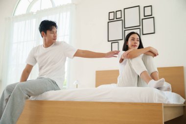 Yatağın kenarında oturan Asyalı çift zor bir konuşmada yol alırken düşünceli bir ifade takınıyorlar. duygusal gerilim.