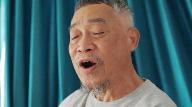 Neşeli bir son sınıf öğrencisi canlı bir mavi perdenin önünde şarkı söyler..