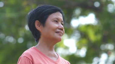 Yüzünde bulanık yeşil yapraklar olan, kıdemli Asyalı kadın..