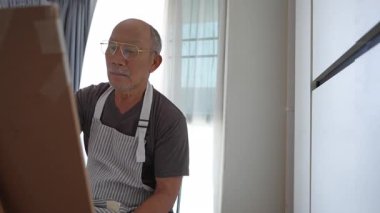 Asyalı bir son sınıf öğrencisi evde resim yapmaya vakit ayırıyor. Emeklilik döneminde yaratıcılığını sergiliyor. Parlak ve davetkar bir yerde.