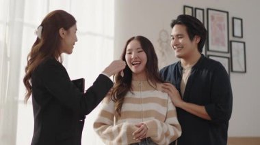 Siyah takım elbiseli Asyalı bir emlakçı genç bir çifte ev anahtarı verip gelecekleri için planlarını ve seçeneklerini tartışıyorlar..