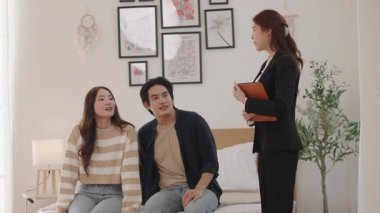 Asyalı çift çağdaş bir yaşam alanında kadın danışman ile sohbet ediyor, gelecek planlarına ve rehberliğine odaklanıyorlar..