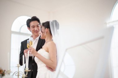 Asyalı gelin ve damat düğün törenlerinde şampanyayla kadeh kaldırıyorlar. Gülümseyin ve kutlayın Zarif odayı doldurun.