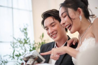 Asyalı çift kameraya bakarken birlikte gülüyor. Saf neşe ve bağ düğün anlarında.