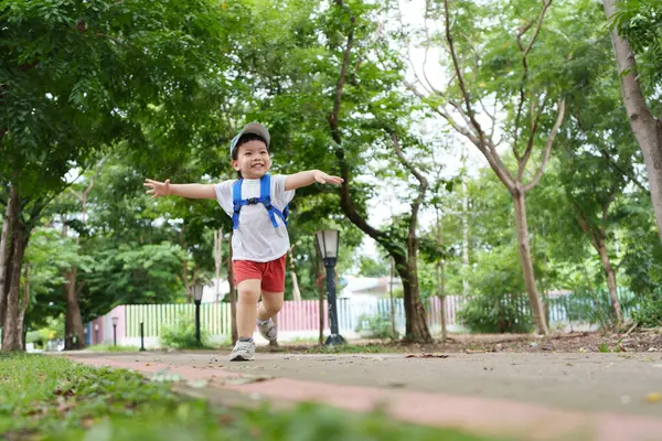 Yeşil parkta kaygısız koşan Asyalı çocuk dışarıda mutlu mesut oynuyor..