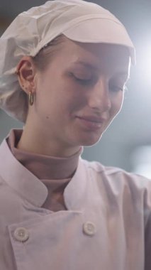 Gülümseyen kadın aşçı restoran mutfağında yemek hazırlamaya odaklanıyor, neşe ve aşçılık becerileri gösteriyor. Kameraya bakıyorum..